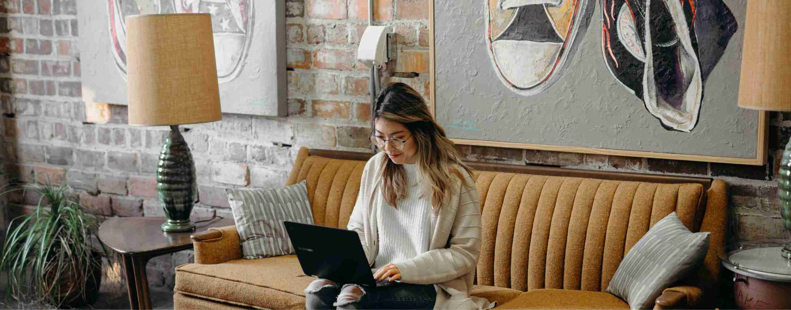 Woman sitting on sofa and using laptop
