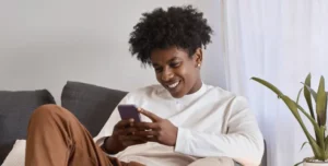 Man holding an iPhone and smiling, expressing satisfaction with the credit card scanning user experience of KeksPay.