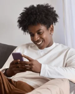 Man holding an iPhone and smiling, expressing satisfaction with the credit card scanning user experience of KeksPay.