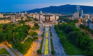 Street view of Sofia, showcasing the main square with notable buildings and bustling activity.